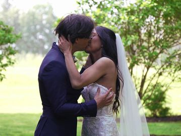Bride and groom share a romantic kiss outdoors on their wedding day.