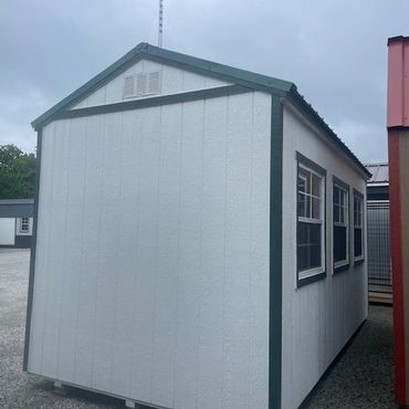 Small white shed with green trim and two windows on the side.