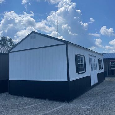 White and black portable building with windows and double doors.