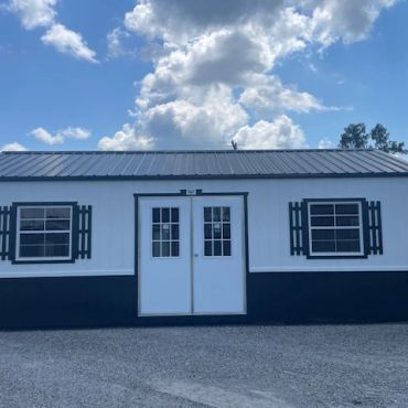White building with double doors and two windows under a blue sky.