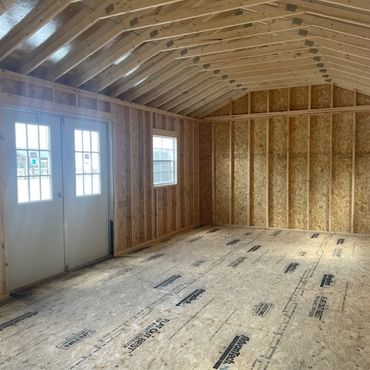 Interior of an unfinished wooden structure with framed walls and roof.
