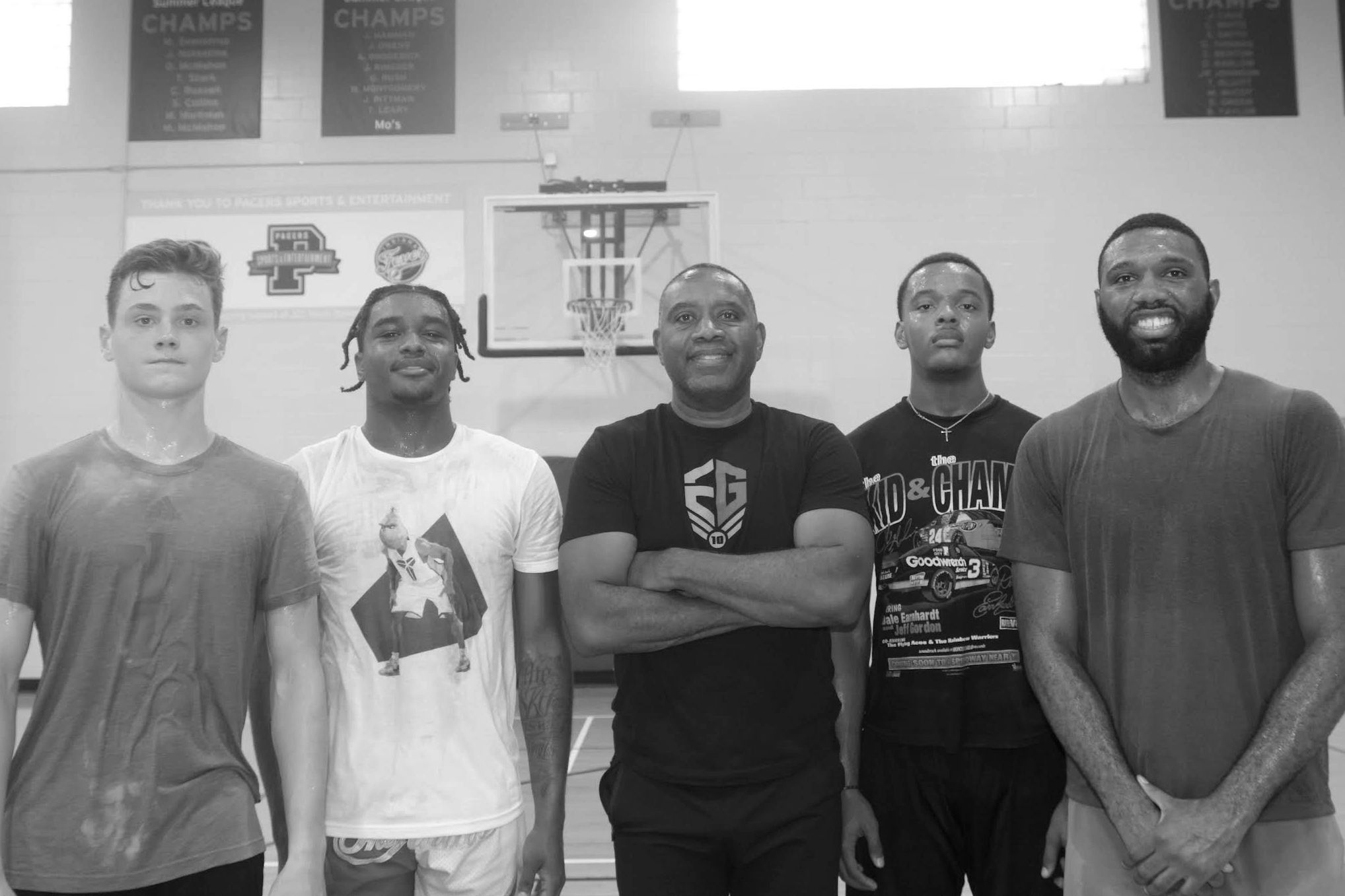 Five men posing in a basketball gym.