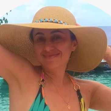 Woman wearing a wide-brimmed hat and colorful swimsuit by the water.