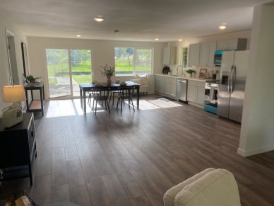 Bright open-concept kitchen and dining area with large windows and wooden floors.