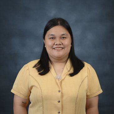 Smiling woman in a yellow blouse against a dark backdrop.
