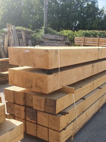 Stack of large wooden beams outdoors at a lumber yard.