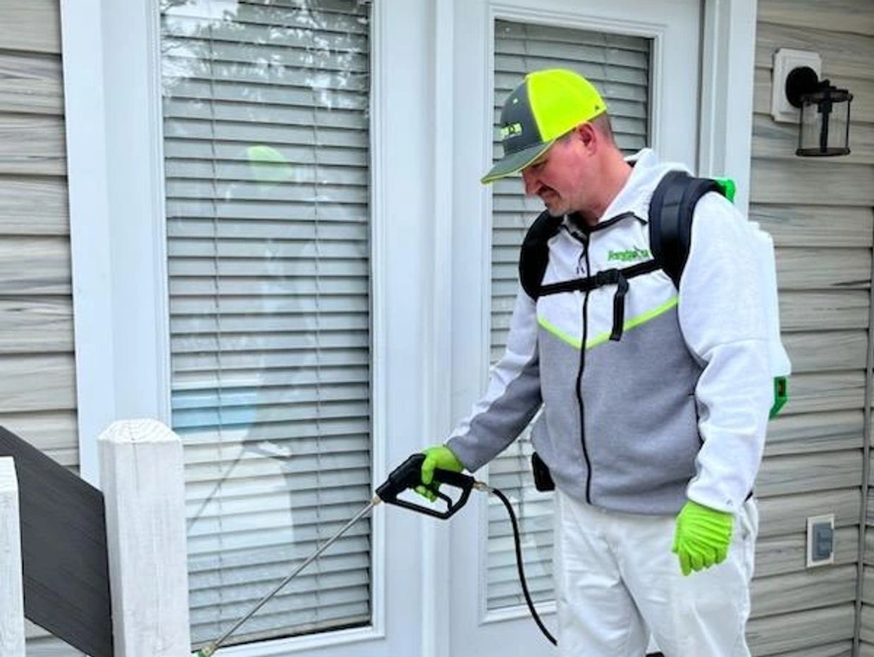 Man spraying pesticide outside a house.
