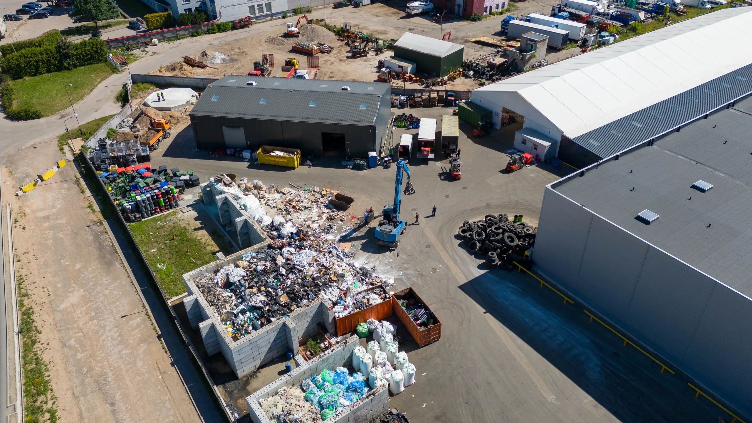 Aerial view of a waste recycling facility with piles of sorted waste and operating machinery.