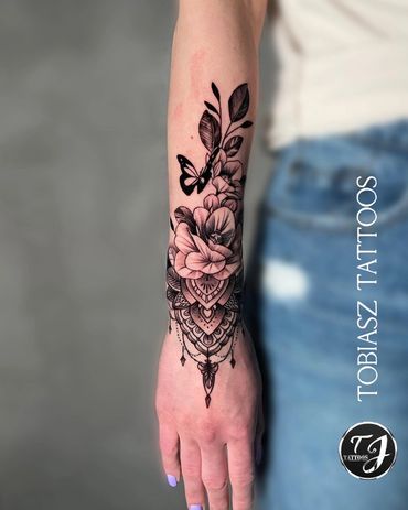 wrist and arm tattoo of flowers and plants with a butterfly