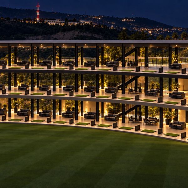 Campo de golf iluminado con plataformas de práctica en varios niveles.