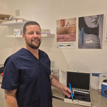 Man in navy scrubs holding a blue CryoPen device in a clinical setting.