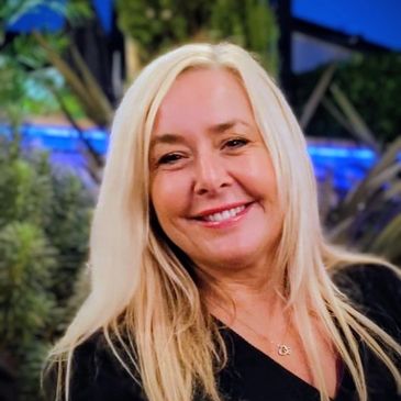 Smiling woman with long blonde hair outdoors at night.