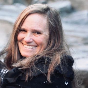 Elena Savage smiling in a headshot. She is wearing a black jacket