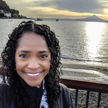 Sophia smiling in front of a waterfront view with a mountain in the background