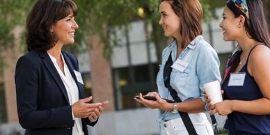 Three women engaging in a friendly outdoor conversation.— Admissions Excellence college consulting