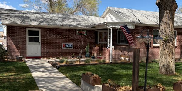 A cozy brick motel office with American flag and "No Vacancy" sign.