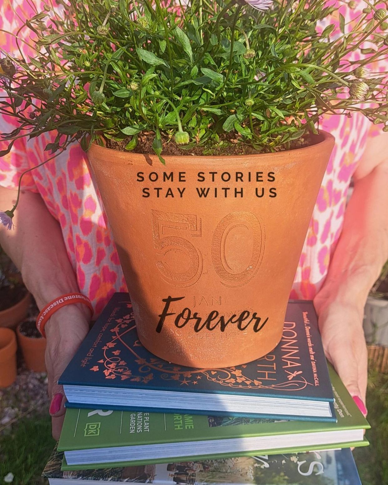 Person holding a plant pot with the text 'Some stories stay with us 50 Forever' and a stack of books.