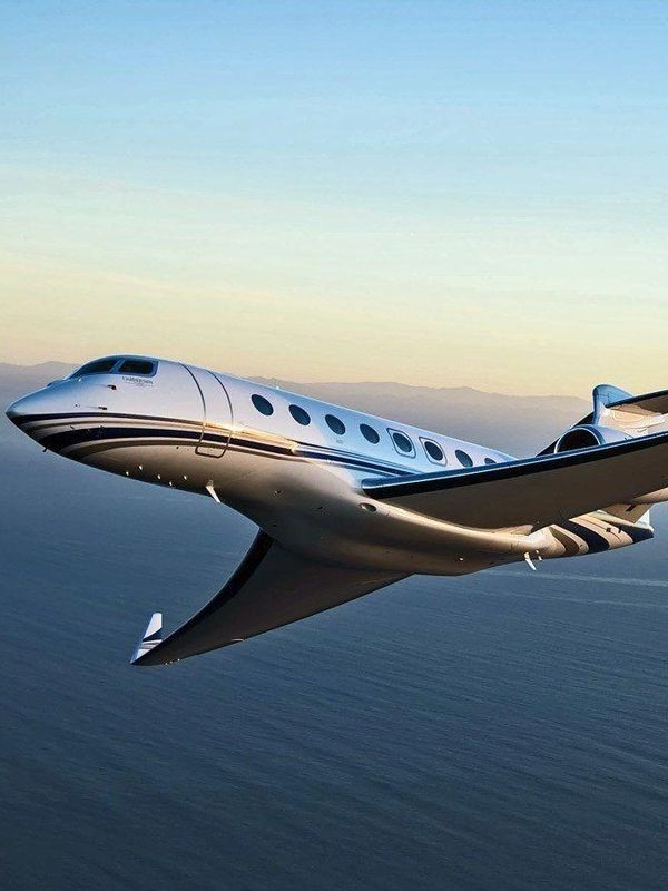 Luxury business jet flying high above the coastline with sleek design.