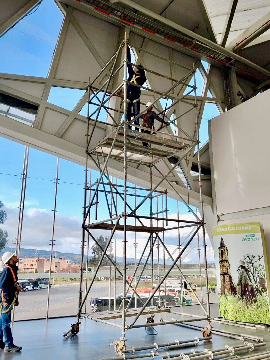 Trabajadores en andamio dentro de un edificio moderno.