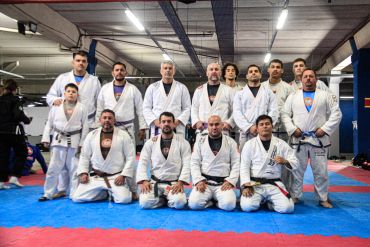 Grupo de praticantes de jiu-jitsu em kimono posando para foto.