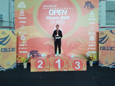 Athlete stands on first place podium at Joinville Open Classic 2026.