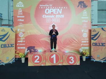 Young athlete stands on the first-place podium at Joinville Open Classic 2026.