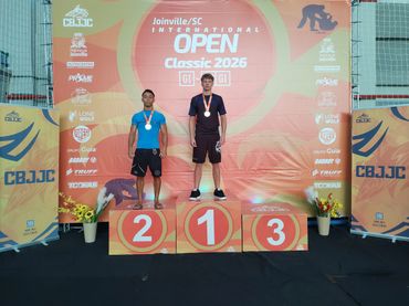 Two athletes stand on a podium at the Joinville International Open Classic 2026 awards ceremony.