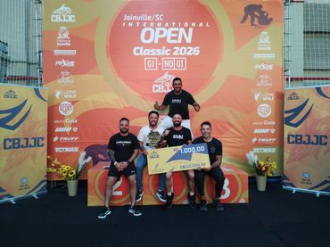 Four men with a trophy and a giant check at Joinville SC Open Classic 2026 podium.