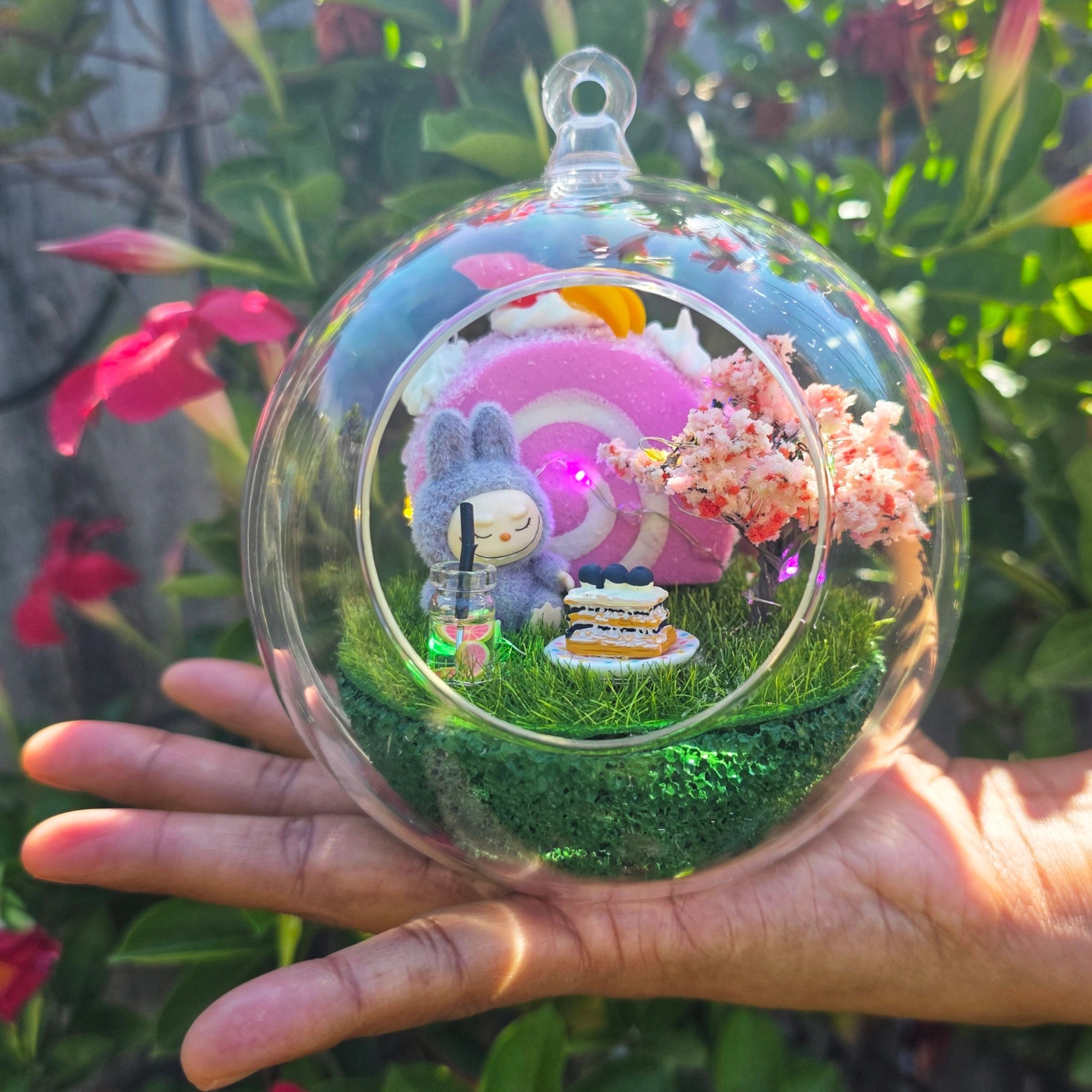 Miniature scene inside a glass orb held over a hand.