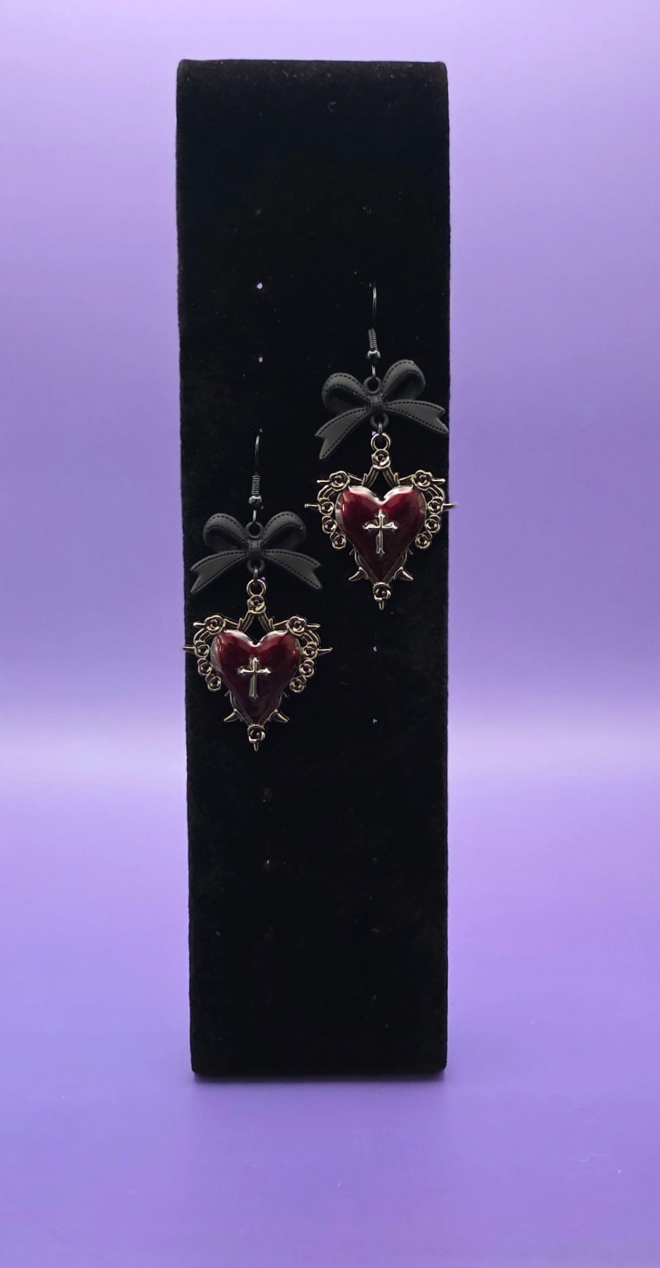Heart-shaped earrings with black bows and cross detail.