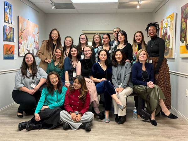 A diverse group of women posing together in an art gallery.