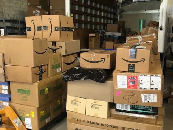 Stacks of cardboard boxes, many bearing the Amazon logo, fill a storage area.