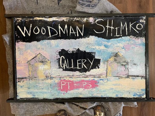 Rustic painted sign for Woodman Shimko Gallery with pastel house images.