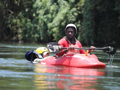 A man kayaking on calm water surrounded by greenery.
