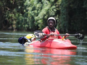 Person kayaking with another wearing a helmet in the water.