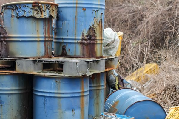 Unlabeled rusted drums with hazardous waste not properly stored as per RCRA compliance. 