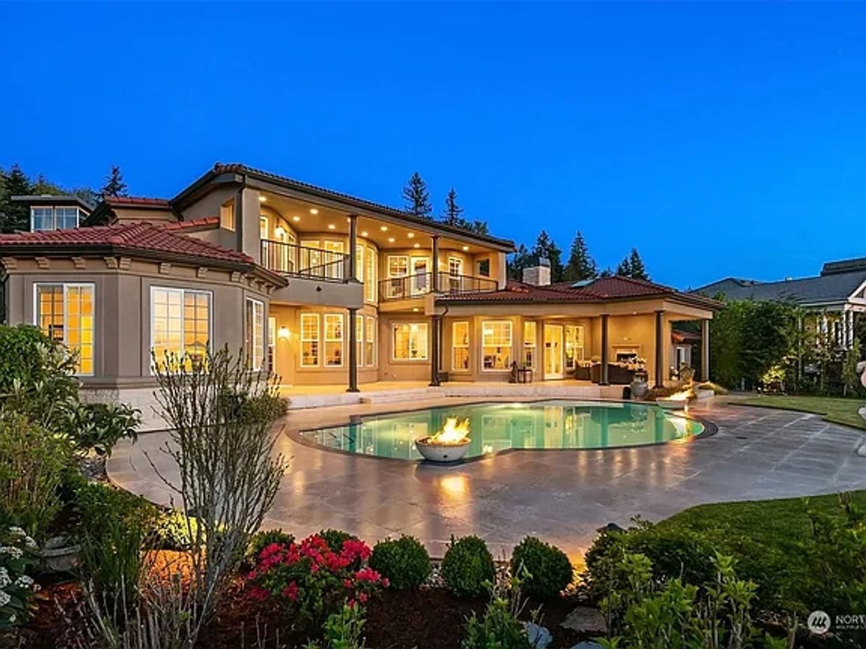 Mediterranean home with pool surrounded by lush vegetation and blooming shrubs.