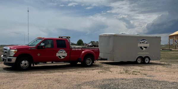 Red truck towing a white trailer with business logos.