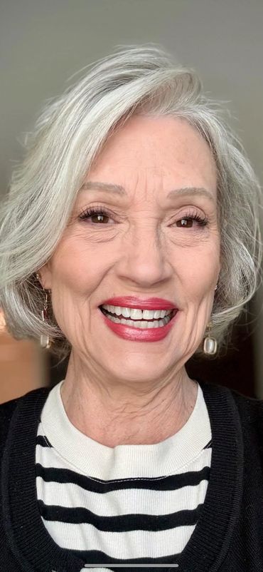 Smiling elderly woman with silver hair and striped shirt.