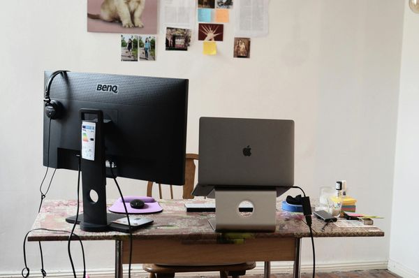 A workspace with a BenQ monitor, a MacBook on a stand, and various desk items.