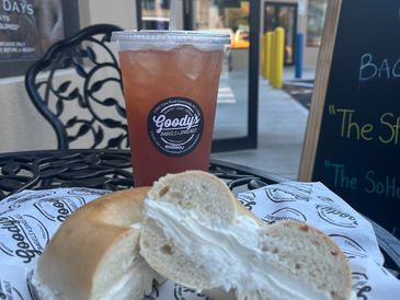 Cream cheese bagel and iced tea from Goody's on an outdoor table.