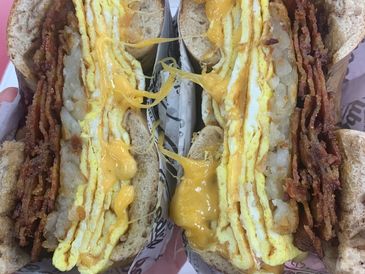 A breakfast sandwich with eggs, cheese, bacon, and hashbrowns.