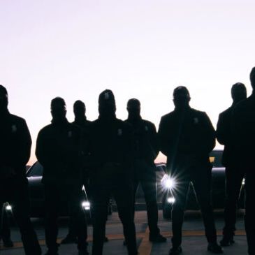 Group of VIP Close Protection officers with security escort vehicles 