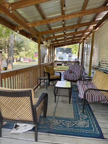Cozy covered porch with outdoor furniture and a rug.