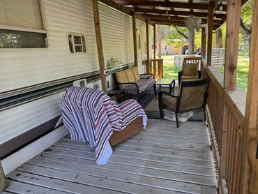 Cozy porch with seating and striped blanket on chair.