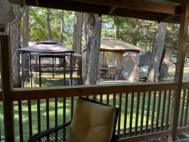 View from a covered porch looking at gazebos and trees.