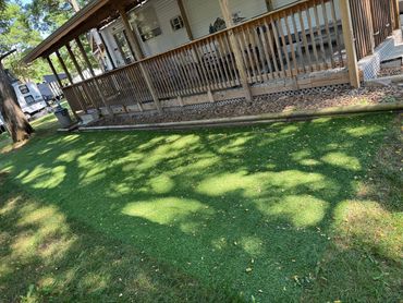 Sunlit artificial grass patch next to a porch.
