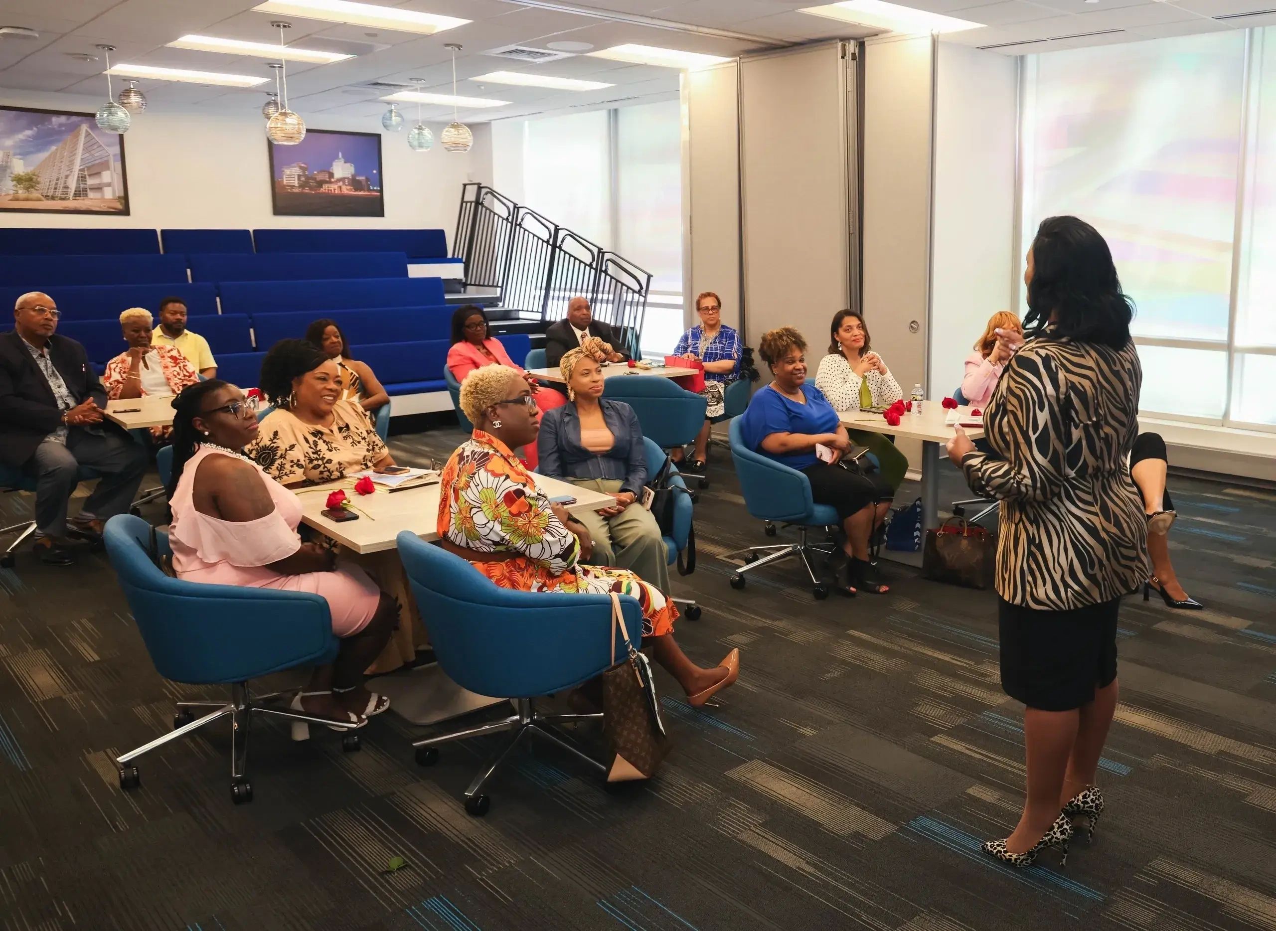 Community workshop with adults seated in a conference room listening to a speaker .