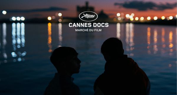Silhouettes of two people by the water at dusk with Cannes Docs Marché du Film logo.