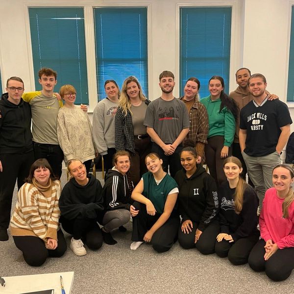 A group of young adults posing together indoors in casual attire.